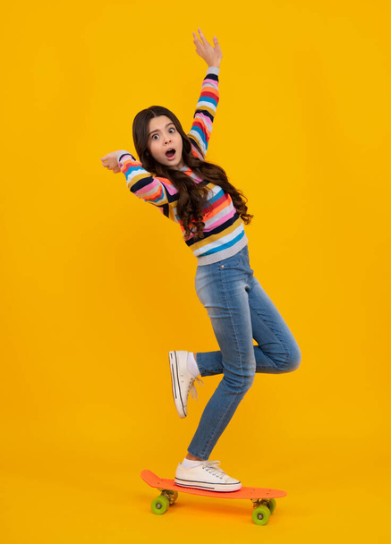 Amazed teenager. Fashion teenage lifestyle, beautiful teen girl with skateboard isolated on studio background. Excited teen girl - 写真・画像