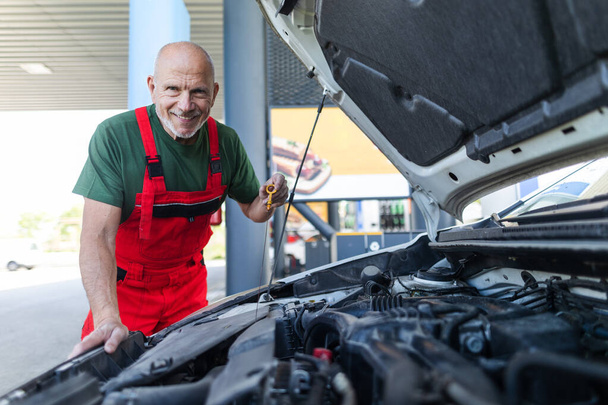 A senior mechanic checking the oil level in the car engine. - Foto, Imagem