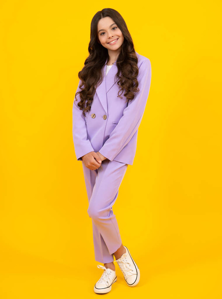 Full length of cheerful teenager child girl wearing comfy trendy fashion clothes, isolated over yellow background. Happy teenager, positive and smiling emotions of teen girl - Valokuva, kuva