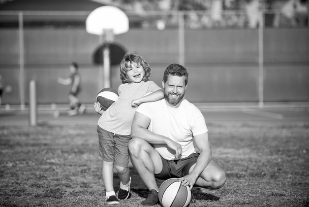 Apa és a kisfiú tartják a sportlabdát. A gyerek kosarazik. gyermekkor és apaság. fiatal játékos edzővel. töltsünk együtt egy kis időt. mosolygó apa és fia a szabadban. Boldog apák napját. családi portré. - Fotó, kép
