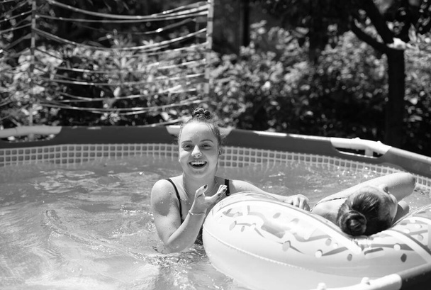 冷たいままだ。幸せな女の子は屋外プールで楽しんでいます。チルプールの日。プールサイドプレイ。夏休みだ。夏. - 写真・画像
