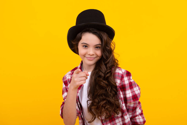 Teenager girl in magician hat, cylinder hat isolated on yellow background. Headwear. Clothes accessories. Fashion headwear for gentlemen in vintage style, old classic cylinder - 写真・画像
