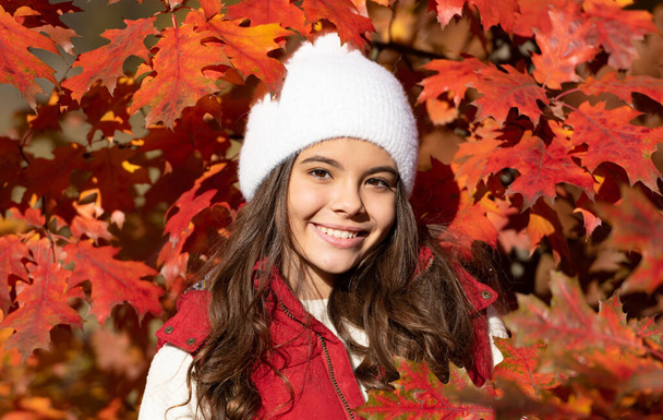 happy teen kid in hat at autumn leaves on natural background. - Foto, afbeelding