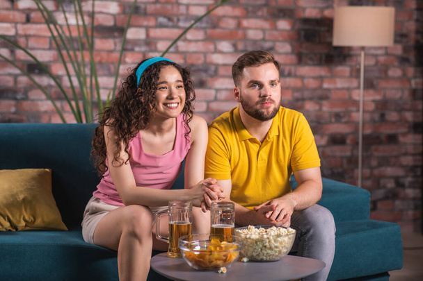 At home in front of tv good looking couple watching a football match together they getting happy when their team are winning they hugging each other and drinking some beer. Portrait - Fotó, kép