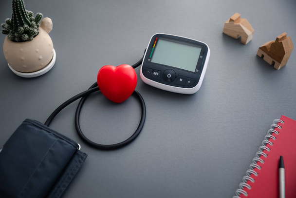 vérnyomás-ellenőrző készülék az önvérnyomás és a pulzusszám mérésére vörös szívvel, egészségügyi ellátással és orvosi koncepcióval - Fotó, kép