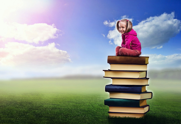 Girl sits on the pile of books - Foto, Imagen