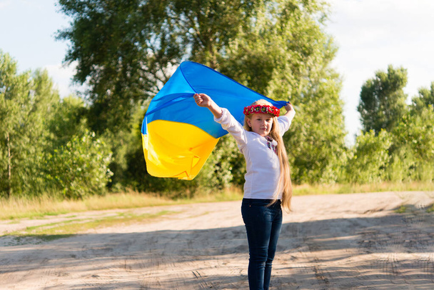 little girl in national Ukrainian clothes - vyshyvanka. Ukraine, child in nature. In the hands of the flag of Ukraine. - 写真・画像