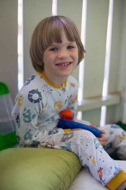 Cute blond boy in pyjama is smiling . High quality photo - Foto, Imagen