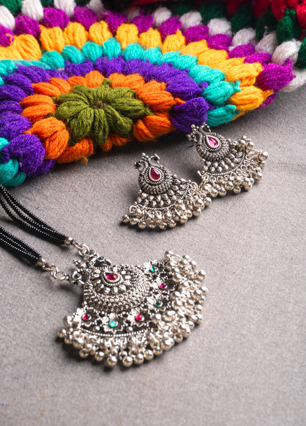 Indian traditional antique or retro style pendant with earrings on colorful knitted background - Foto, immagini