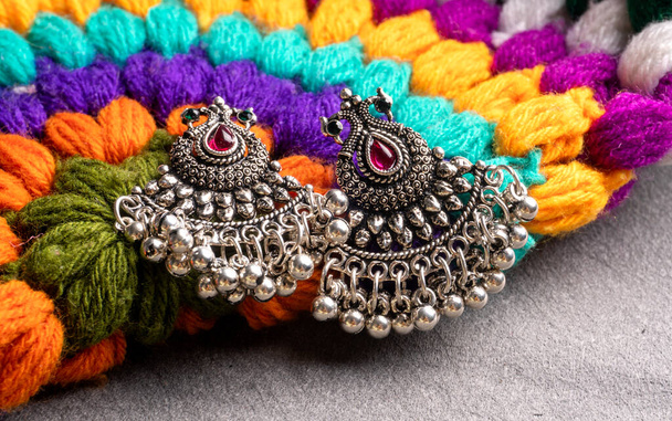 Indian traditional antique or retro style earrings on colorful knitted background - Фото, изображение