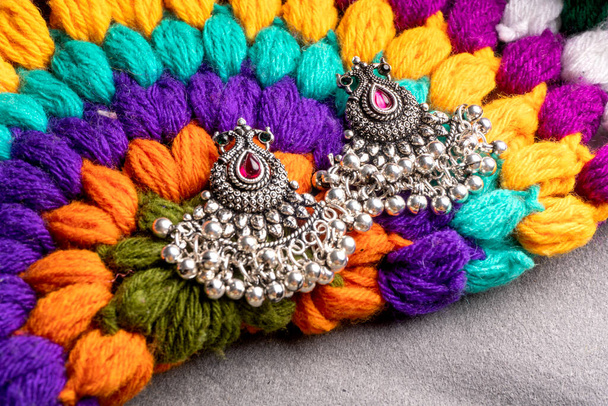 Indian traditional antique or retro style earrings on colorful knitted background - Фото, изображение