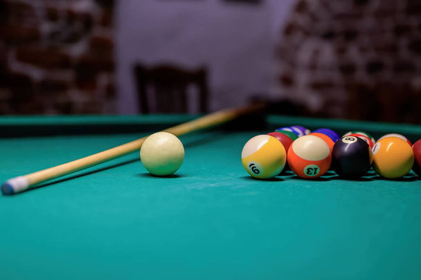 Більярдний стіл з м'ячами, м'ячем і києм у клубі. стіл з зеленою кришкою
. - Фото, зображення