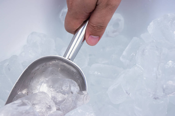 The hand holding an ice cube scoop. - Fotó, kép