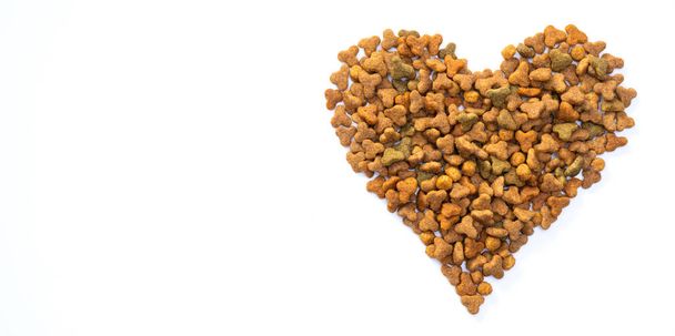 Valentines day and love of pets concept. Heart shaped cat dry kibble food on white background. High quality photo - Foto, immagini