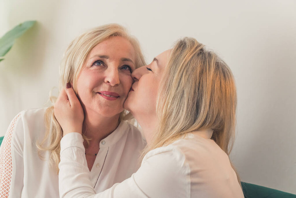 una mujer besándose la otra en una mejilla primer plano sala de estar pareja femenina. Foto de alta calidad - Foto, Imagen