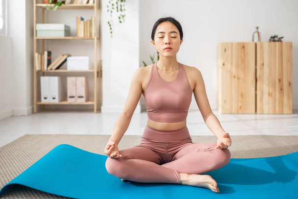 Asian female sitting on mat lotus pose do yoga exercise - Mindfullness and healthy lifestyle - Fotoğraf, Görsel