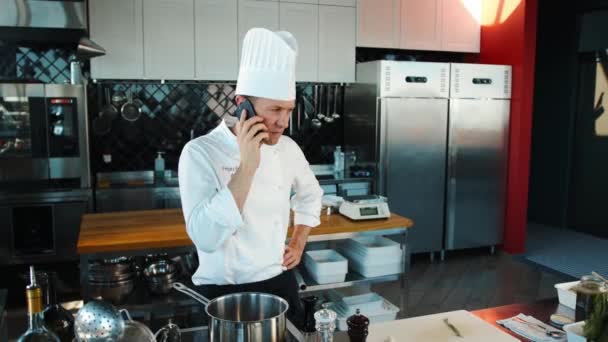The chef is talking on the phone in kitchen. - Filmagem, Vídeo