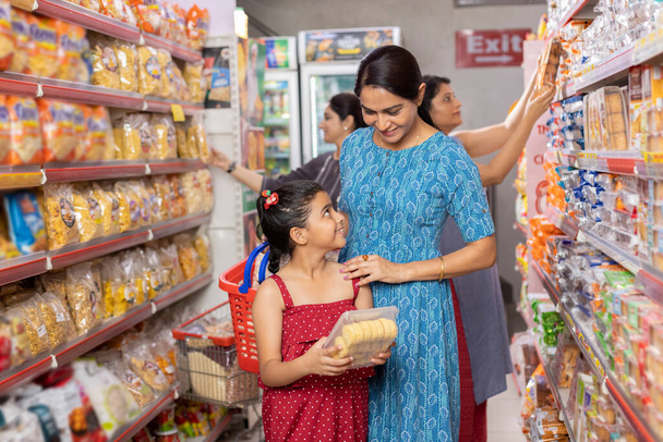 Onnellinen äiti ja tytär lukemassa tuotetietoja ostoksia supermarketissa - Valokuva, kuva