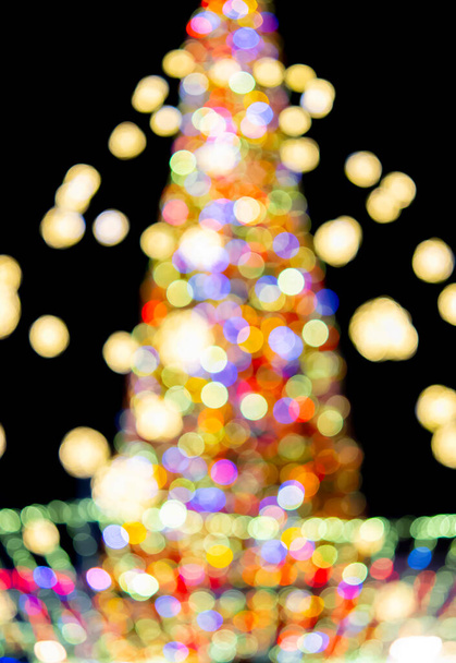 Μεγάλο χριστουγεννιάτικο δέντρο Πρωτοχρονιάς διακοσμημένο με φωτεινές πολύχρωμες γιρλάντες και φωτισμό τη νύχτα. Χριστουγεννιάτικο δέντρο με αναβοσβήνει φώτα. Θολή ιστορία. Πρωτοχρονιά και γιορτές Χριστουγέννων - Φωτογραφία, εικόνα