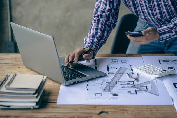 Close-up of a man working on a project sketching architects on blueprints at a construction site. Architect, engineer concept in desk construction project bannerclose-up of drawing plans with architect equipment - Φωτογραφία, εικόνα