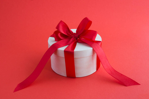Wooden gift box with tied red bow on the red background. Closeup. - Photo, image