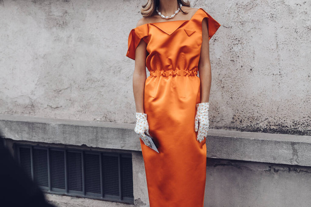 MILAN, ITALY - FEBRUARY 24, 2022: Elegant woman wearing orange long dress, black bag and white gloves. - Fotografie, Obrázek