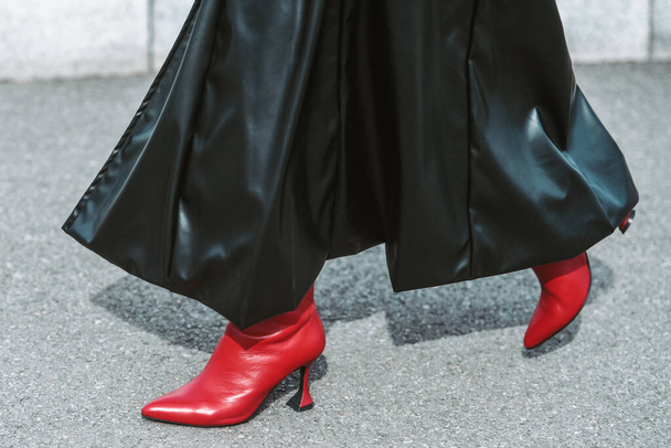MILAN, ITALY - FEBRUARY 24: Street style outfit - woman wearing black leather skirt and red shoes. - Foto, imagen