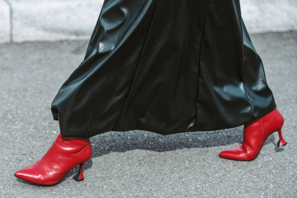 MILAN, ITALY - FEBRUARY 24: Street style outfit - woman wearing black leather skirt and red shoes. - 写真・画像
