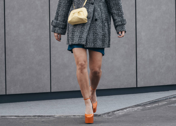Milan, Italy - February, 24: Street style, woman wearing yellow shiny leather crocodile bag, blue dress and orange shoes. - Foto, imagen
