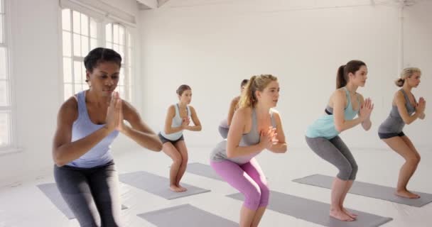 4k video di un gruppo di giovani donne che si esercitano in uno studio di yoga insieme. - Filmati, video