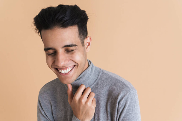 Young middle eastern man wearing turtleneck laughing at camera isolated over beige background - Фото, зображення
