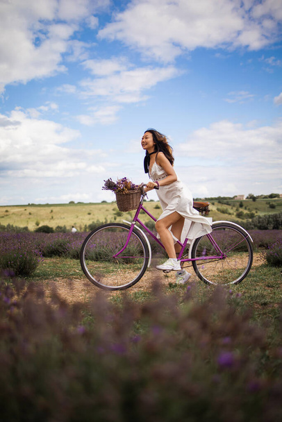 Young asian girl with a bicycle walks on a lavender field. - Фото, зображення