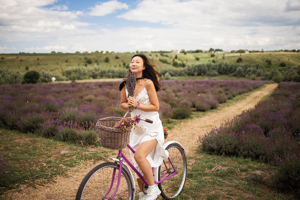 Young asian girl with a bicycle walks on a lavender field. - Foto, Imagem