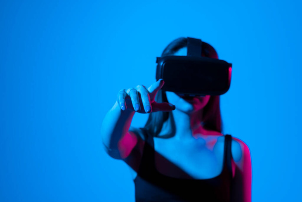 Excited young woman in VR headset exploring artificial computer world or playing video game at home and touching something in virtual reality - Foto, Imagem