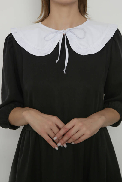 Fiatal női modell fotósorozata fekete ruhát viselő fehér Peter pan levehető gallérral. - Fotó, kép