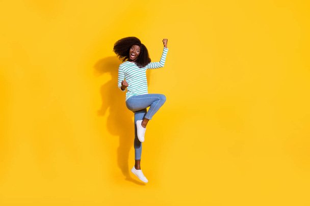 Full size photo of overjoyed satisfied person jumping raise fists celebrate luck isolated on yellow color background. - 写真・画像