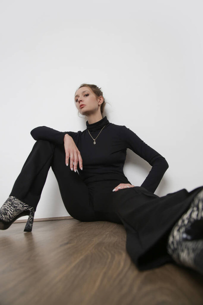 Serie studiofoto 's van jong vrouwelijk model met alle zwarte klassieke basic outtfit, stretch viscose coltrui en basic flared broeken.  - Foto, afbeelding