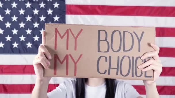 Happy young woman holds hand written protest sign My Body, My Choice at womens march. Group of females demonstrating outdoors - Video