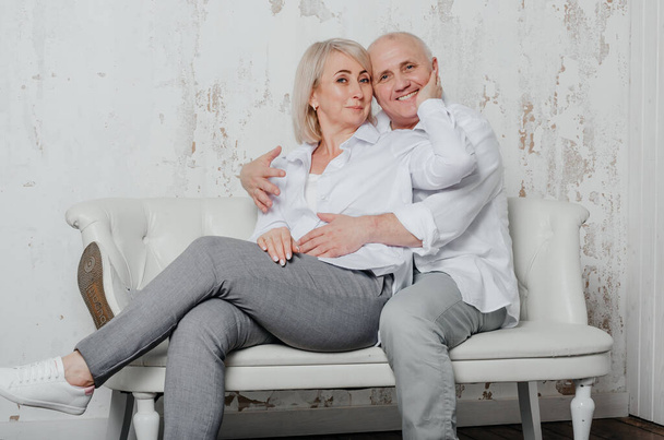 a man and his wife in white shirts on the couch - Foto, Imagem