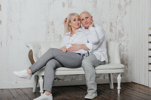 egy férfi és a felesége fehér ingben a kanapén - Fotó, kép