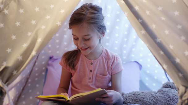 Happy preteen kid reading book in wigwam at home  - Photo, Image