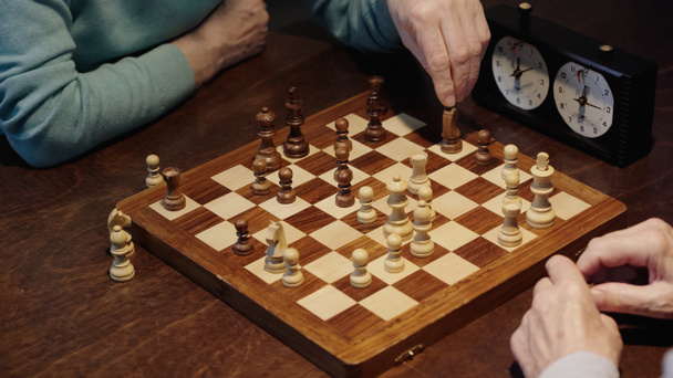 partial view of man moving chess figure while gaming with senior friend - Photo, Image