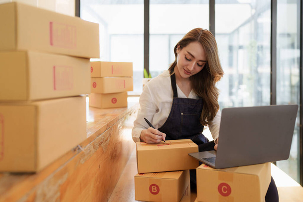 Young Asian woman at warehouse to delivery to Entrepreneur owner SME. Business digital online SME small business and online shop - Φωτογραφία, εικόνα