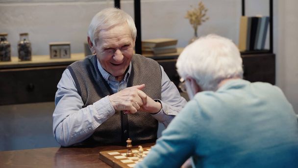 laughing man playing chess with senior friend on blurred foreground - 写真・画像