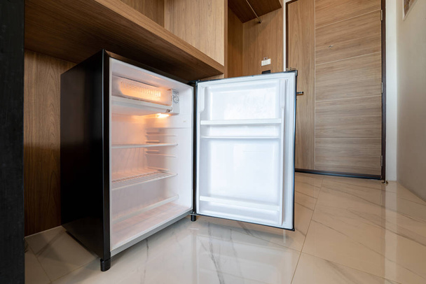 Opened small refrigerator under the wood counter and in front of enter door delux room at resort and hotel. - Valokuva, kuva