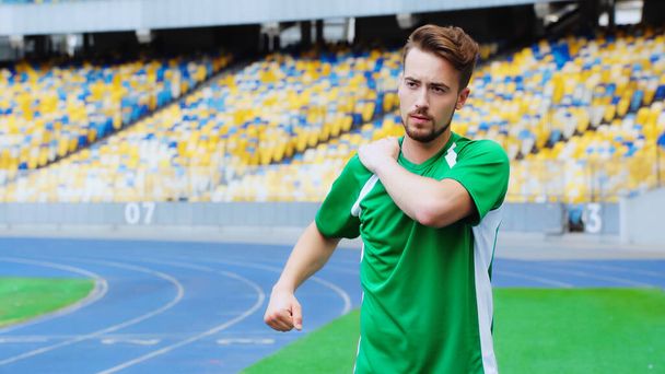 young football player in green t-shirt warming up on stadium - Photo, image