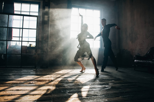 Couple of two professional ballroom dancers is dancing on loft studio. Beautiful art performance with heavy smoke. Sport life concept. Passion and emotional dance. - Photo, Image