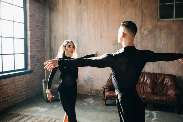 Couple of two professional ballroom dancers is dancing on loft studio. Beautiful art performance. Sport life concept. Passion and emotional dance. - Photo, image