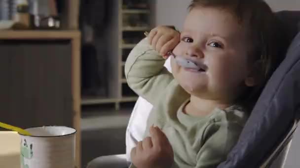 Cute caucasian baby girl eating yogurt at home. Baby care. Healthy breakfast. - Filmati, video