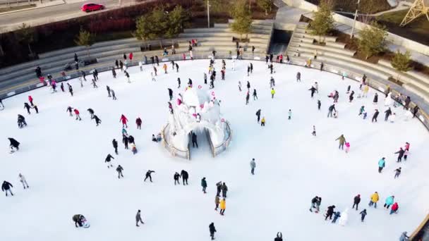 Many people are skating on a white outdoor ice rink in the city on winter day. People skating on the surface of a white ice rink. Aerial drone view. Top view. Lifestyle, sport, rest - Metraje, vídeo